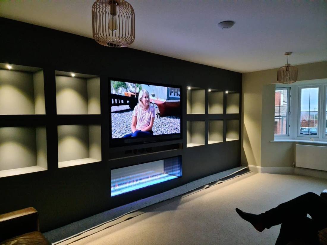 Media wall with lit alcoves, TV and fireplace