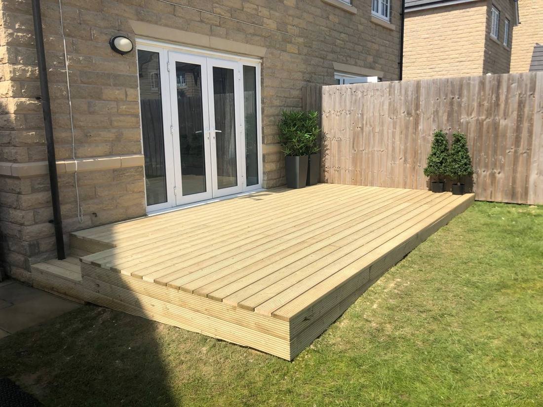 Timber decking by French doors on a stone house